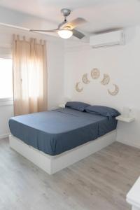 een slaapkamer met een bed met blauwe lakens en een plafondventilator bij Tossa Sunny in Tossa de Mar