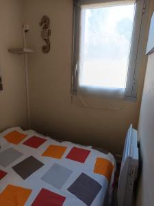 a bed in a room with a window and a bedspread at Casa Marina - Le Petit Bleu Vue mer in Pornic