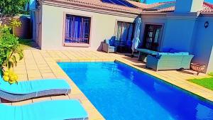 a blue swimming pool with chairs and a house at 5 On Dana in Gqeberha