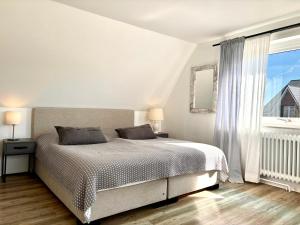a white bedroom with a bed and a window at Strandhaus Wackerballig in Gelting