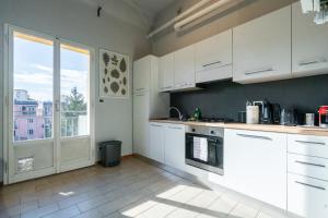 ボローニャにあるIndipendenza Loft City Centerの白いキャビネットと大きな窓のあるキッチン