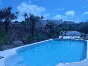 a large swimming pool in a yard with palm trees at Studio "LA MEDINA", au coeur d'un merveilleux jardin, proche COMMERCES & MER in Surtainville