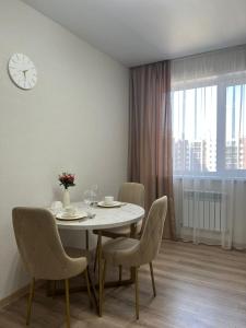 a dining room with a table and chairs and a clock at 1 комнатная квартира в микрорайон Аэропорт in Kostanay