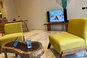 a living room with two chairs and a table and a tv at Xaana Private Pool 2 bed wifi 300 Mbps Rooftop in Tulum