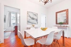 a white dining room with a white table and white chairs at Prime Location Upper Manhattan Furnished Apartment in New York