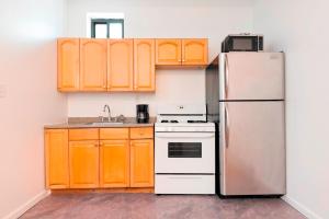 a kitchen with orange cabinets and a refrigerator at Prime Location Upper Manhattan Furnished Apartment in New York +4 photos