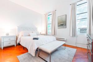a white bedroom with a bed and a bench at Prime Location Upper Manhattan Furnished Apartment in New York