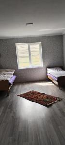 a room with two beds and a rug on the floor at Xinaliq Khinalig ELNUR GUEST HOUSE, New hotel in Xınalıq