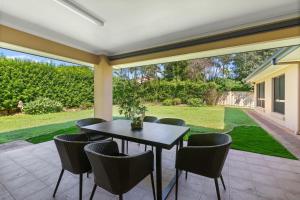 a patio with a table and chairs and a yard at 4BSpacious Cozy Family Entertained home at Parkinson in Browns Plains