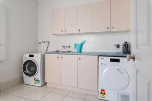 a kitchen with white cabinets and a washer and dryer at 4BSpacious Cozy Family Entertained home at Parkinson in Browns Plains