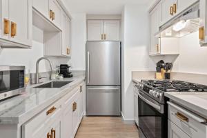 a kitchen with white cabinets and a stainless steel refrigerator at Seaside and Newly Renovated in Summerland