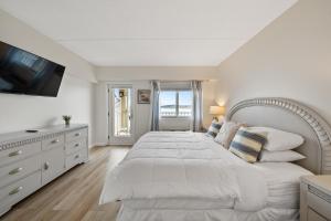 a white bedroom with a large bed and a television at Bella Vista Suites Lake Geneva in Lake Geneva