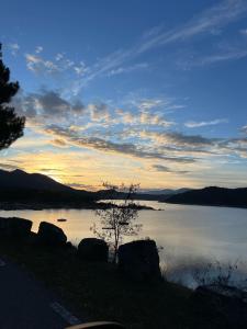 un tramonto su un lago con rocce e un albero di Hostal Las Cruceras a Las Cruceras
