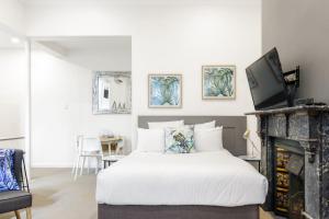 1 dormitorio con cama blanca y chimenea en Huge Designer Studio Next to Lovely Park, en Sídney