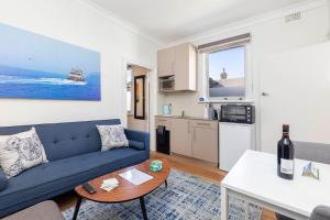 Una sala de estar con un sofá azul y una cocina. en Charming 1 bedroom, park adjacent. city 5 minutes, en Sídney
