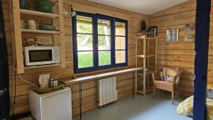 a kitchen with wooden walls and a microwave and a window at La cabane, Chambre indépendante dans jardin - Esprit cabane authentique et confortable - la campagne à 5 mn du centre de Caen in Fleury-sur-Orne