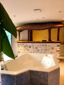 a bath tub in a room with a tile wall at Mon Jacuzzi privé sur les pas de Compostelle in Saint-Léonard-de-Noblat