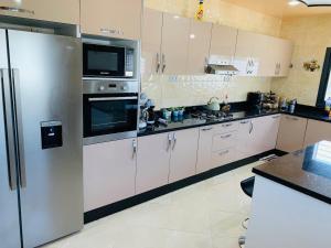 a kitchen with white cabinets and stainless steel appliances at Al confort in Fez