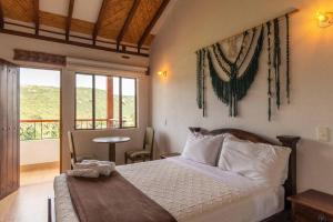 a bedroom with a bed and a table and windows at Artemisa Hotel Villa de Leyva in Santa Sofía +40 photos