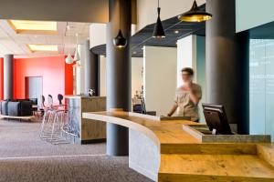 a man walking through an office lobby with a reception counter at ibis Vichy in Vichy