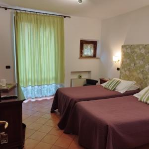 a hotel room with two beds and a window at Arca Hotel in Pienza