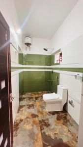 a bathroom with a white toilet and green walls at Wayanad Haven Villa in Wayanad +42 photos