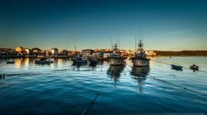 a group of boats are docked in the water at Os Boliños in Camariñas