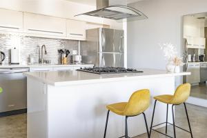 a white kitchen with two yellow chairs at a counter at Angel City 1 bedroom Apartment in Los Angeles