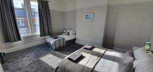 a room with two beds and a window at Free Parking, Fast WIFI, Fully Equipped Kitchen, 15 min drive to Nissan, 20 min to Newcastle Sunderland, Ideal for Long Term Contractor etc Stays, Regular Housekeeping Option - Dwellcome Home Ltd 4 King Bedroom Townhouse - See Our Site for Assurance in South Shields