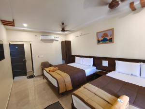 a hotel room with two beds and a bathroom at Hotel DKR Grand in Tirupati
