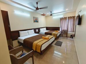 a hotel room with two beds and a couch at Hotel DKR Grand in Tirupati