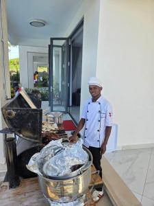 a man standing in a kitchen with some food at Infinity Pool Villas, Entebbe airport shuttle, free parking large private pool Wifi 24 hr security in Entebbe +70 photos