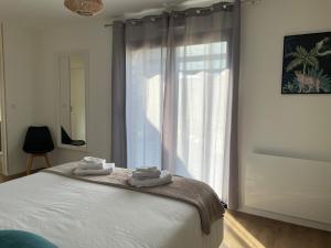 a bedroom with a large window with towels on a bed at Villa Egurra, à proximité d'une plage de sable fin in Santec +33 photos