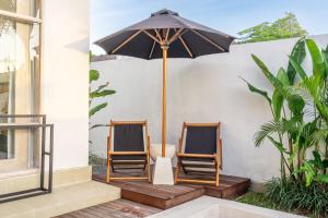 two chairs and an umbrella on a porch at La Palma - Sleek, Stylish & Spacious - Brand New 2-Bedroom Villa with Large Pool in Canggu! in Canggu