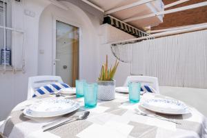 a white table with plates and blue glasses on it at Casa Nova - a 2 min de la playa in Santa Pola