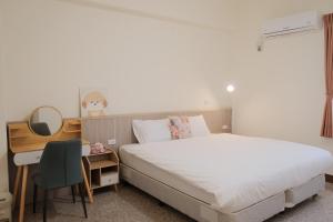 a bedroom with a bed and a desk and a bed sidx sidx sidx at Pick Inn in Taitung City