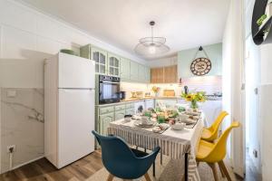 cocina con mesa con sillas y nevera blanca en Maria Home Reall's, en Braga