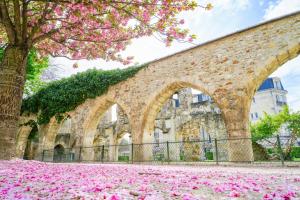 a brick wall with pink flowers in front of a building at CLASSIC HÔTEL Reims Est - Taissy in Reims