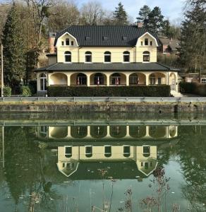 a large house with a reflection in the water at Maison Meuse in Waulsort