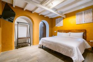 a bedroom with a white bed in a yellow wall at Casa Xaca in San Miguel de Allende