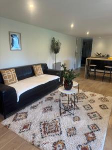 a living room with a black couch and a rug at Appartement au cœur du golf in Pont-de-Larn