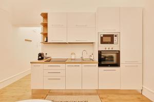 a white kitchen with white cabinets and a sink at Casa di borgo in Rome