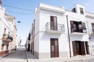 a white building with brown shutters on a street at Appartamento Marina a due Passi dal Mare in San Vito lo Capo