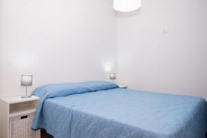 a bedroom with a blue bed and a night stand at Appartamento Marina a due Passi dal Mare in San Vito lo Capo
