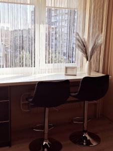 a desk with two chairs in front of a window at LuXury Apartment on Naujakiemis Street in Klaipėda