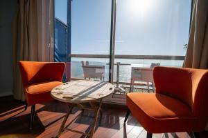 a room with two chairs and a table and a large window at LOGIS HOTEL - La Petite Rade in Le Havre
