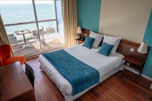 a bedroom with a bed with a view of the ocean at LOGIS HOTEL - La Petite Rade in Le Havre