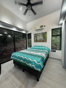 a bedroom with a bed in a room with windows at Plaza Tucanito - jungle up your life in Cahuita