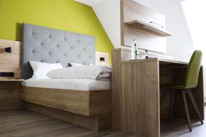 Schlafzimmer mit einem Bett, einem Schreibtisch und einer grünen Wand in der Unterkunft Wallfahrtswirt in Wemding
