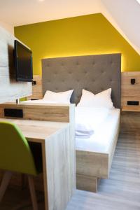 ein Schlafzimmer mit einem Bett, einem Schreibtisch und einem Fernseher in der Unterkunft Wallfahrtswirt in Wemding